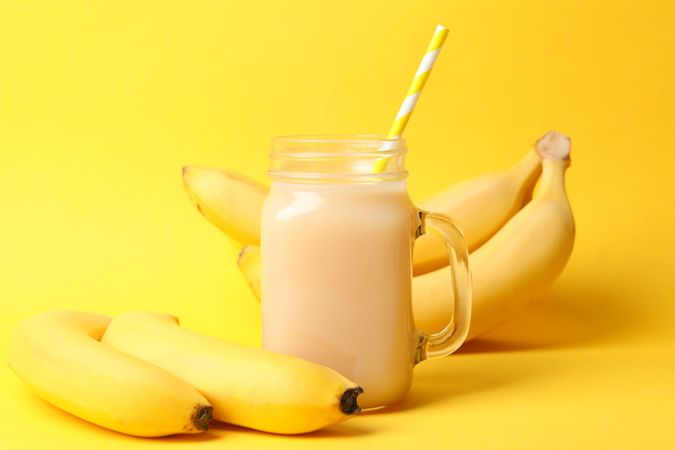 Bananas and juice on yellow background. Fresh fruit