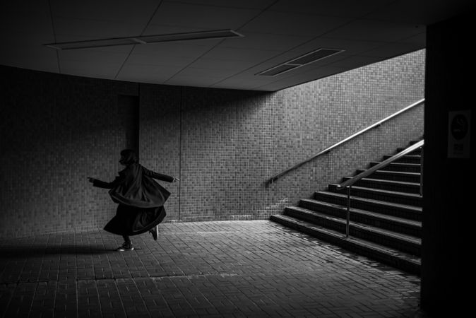 Grayscale photo of person walking near stairs