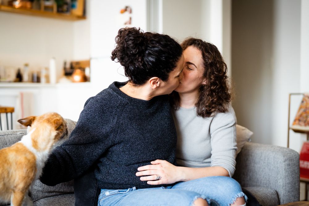 Wives tenderly kissing on sofa at home