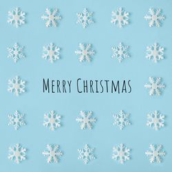 Snowflakes arranged on blue background with “Merry Christmas”