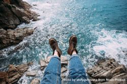Hiker sitting on rocks overlooking ocean in leather boots, landscape 4N7rZb