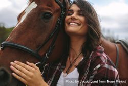 Close up of happy young woman hugging her horse 0Vva30