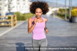 Black woman, with afro hairstyle, running outside in city road 0yL9Gb