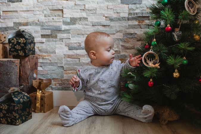Cute baby playing with Christmas tree baubles