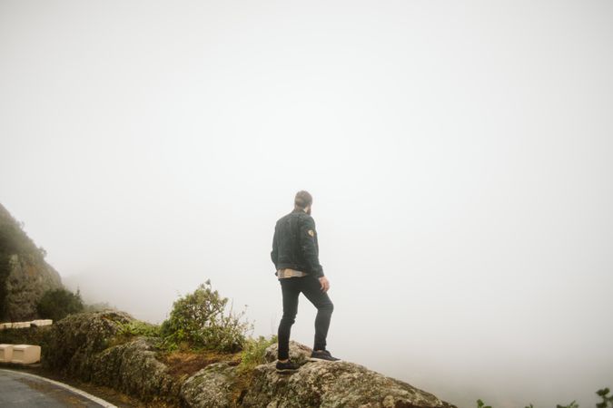 Anonymous man standing on cliff near countryside road