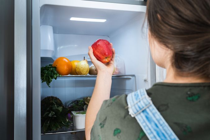 Crop woman taking fruit from fridge