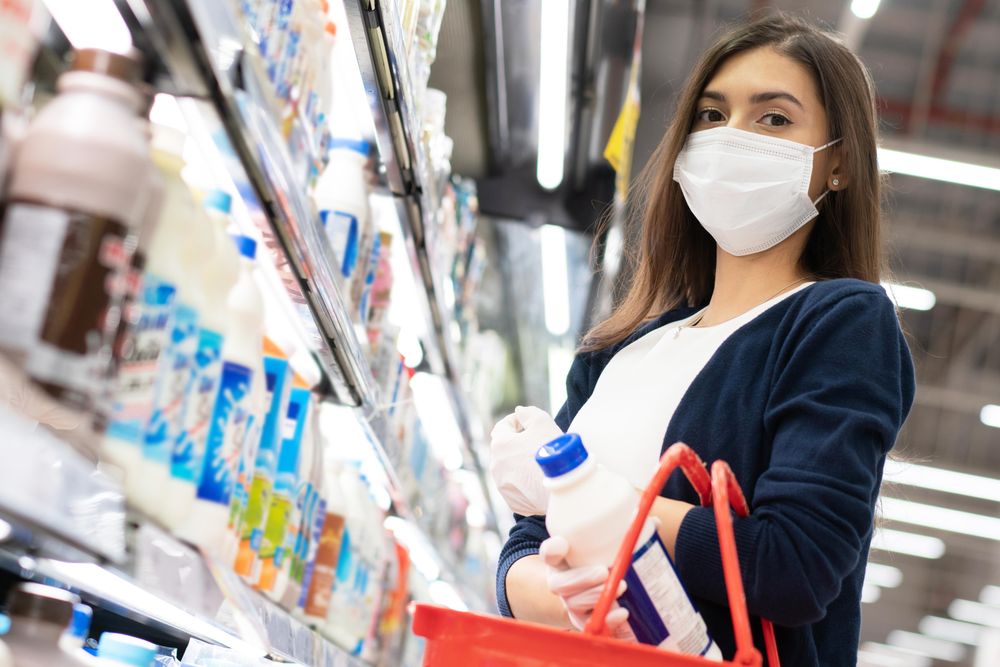 Woman picking up milk at grocery shopping in surgical mask