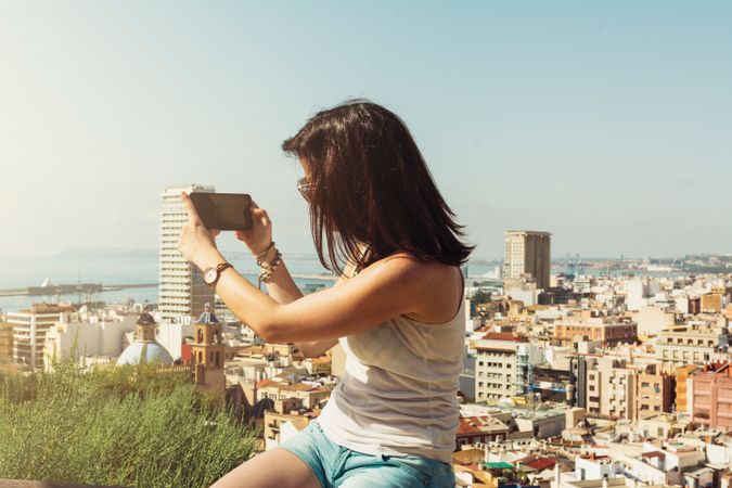 Woman on balcony taking pictures city views from above
