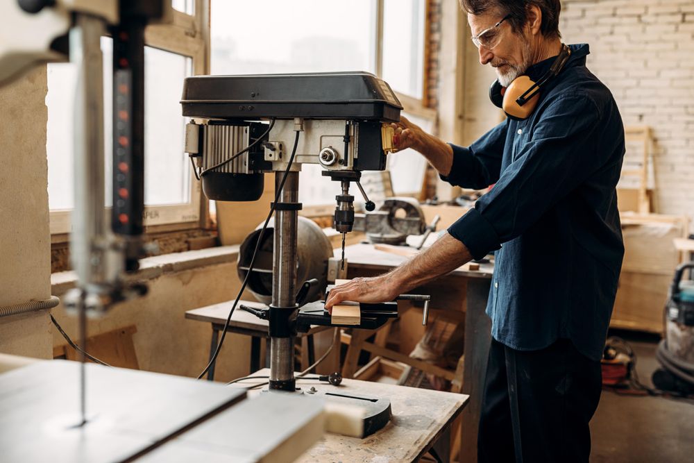 Carpenter drilling wood on machine