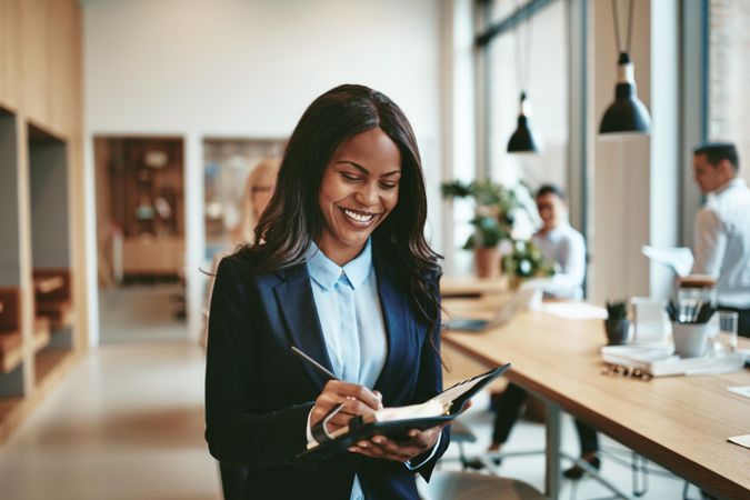 Woman smiling with notepad in open office