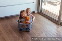 Beautiful young children sitting in a washing basket at home 48G9q5