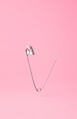 Close up of one opened safety pin on pink background