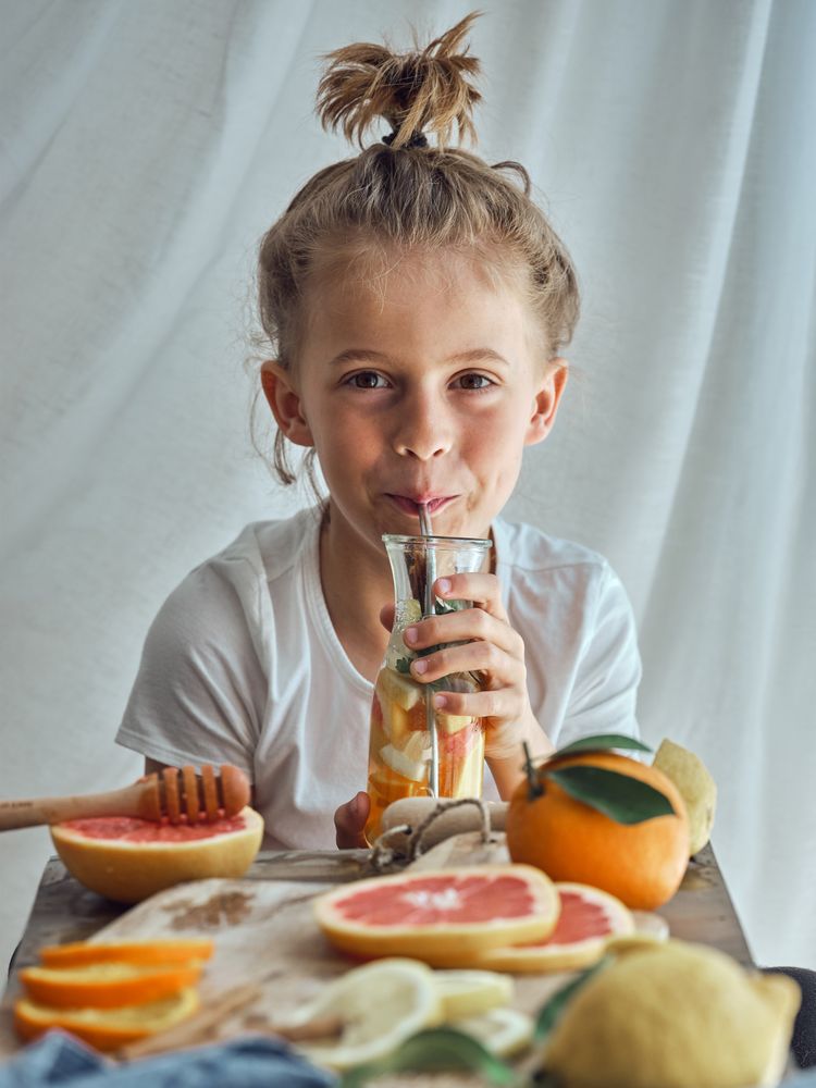 Smiling little boy sitting at table and drinking juice