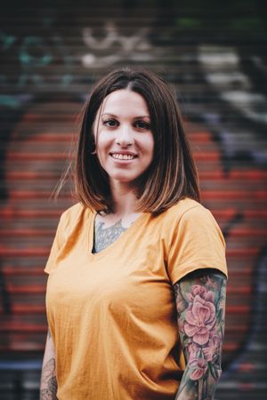 Cheerful tattooed woman smiling and standing on street