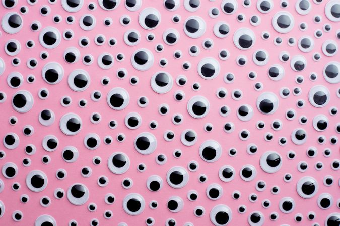 Scattered googly eyes on pink background