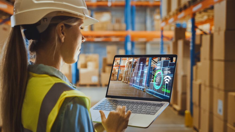 Futuristic Technology Warehouse: Female Worker Doing Inventory, Using Augmented Reality Program On Laptop Computer.