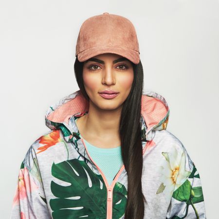 Determined woman pictured in colorful printed floral hoodie wearing a cap