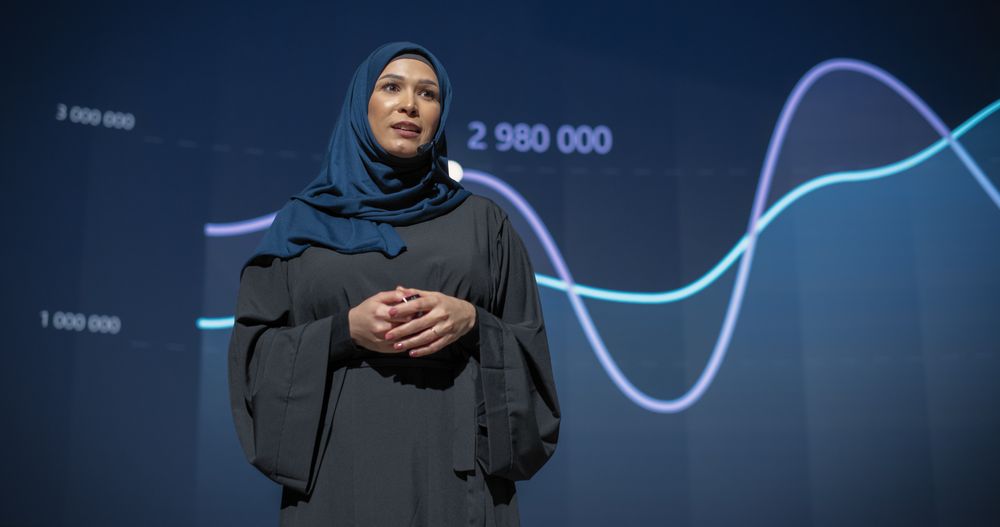 Female Business Executive Introduces New Software Product on Stage at a Conference.