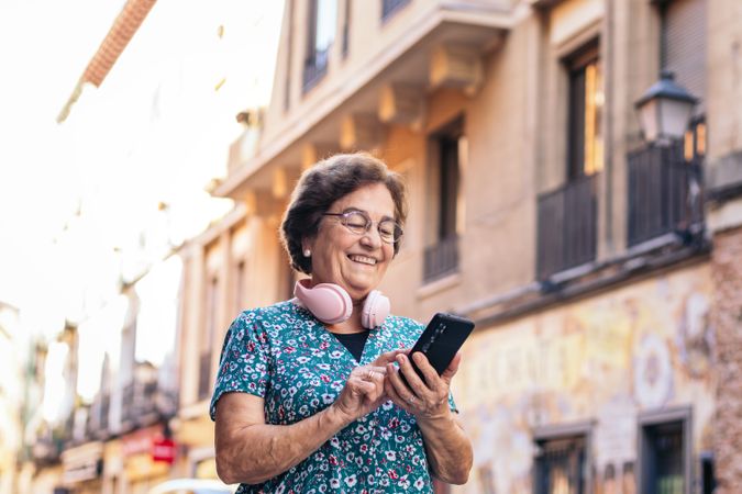 Smiling older woman using smartphone outdoors