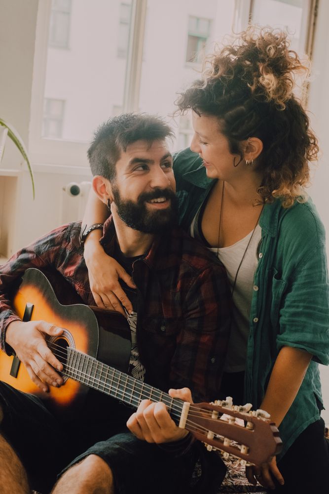 Cheerful couple playing guitar at home