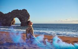 Young man on beach with blue smoke