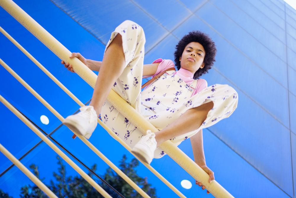Low angle shot looking up at woman sitting on handrails in front of reflective corporate building