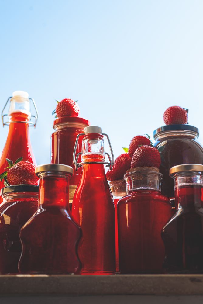 Glass bottles and jars with strawberries syrup