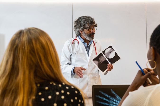 Mature doctor discussing x ray with colleagues in hospital