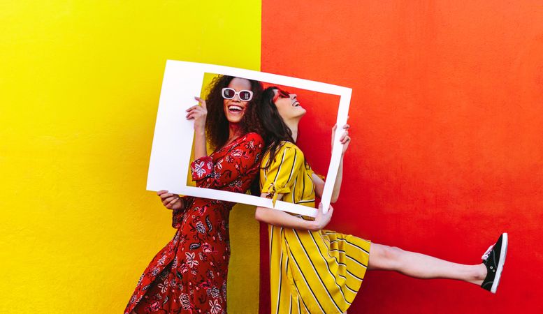 Playful friends posing in front of bright colored wall