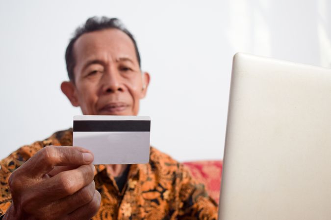Asian man looks at blank credit card