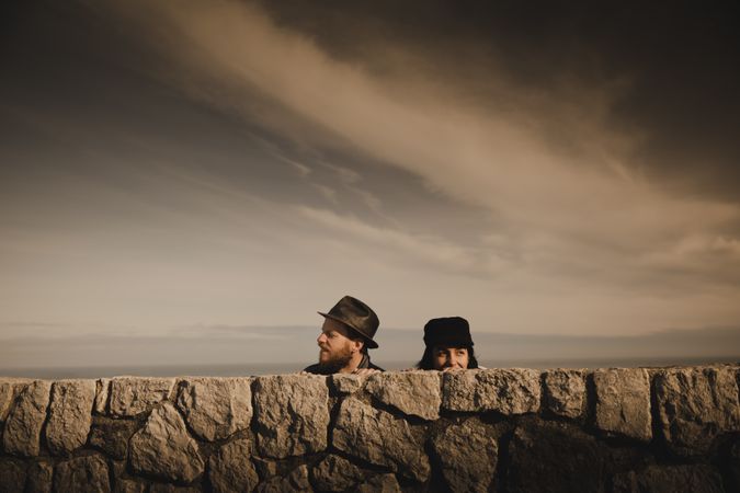 Man and woman leaning out from stones