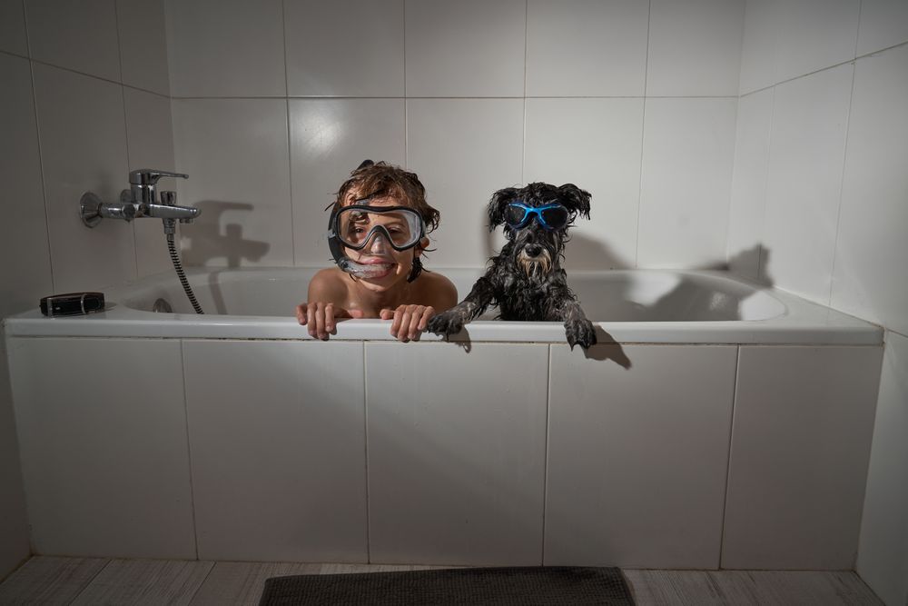 Boy in diving mask near dog in tub