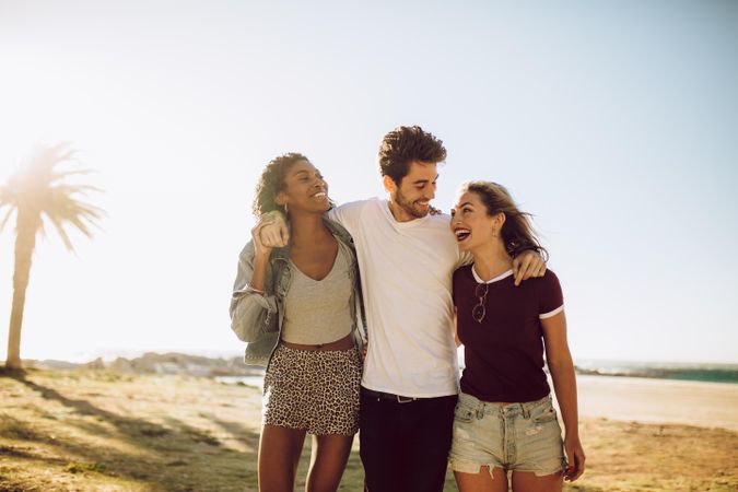 Young man with female friends walking outside on summer day