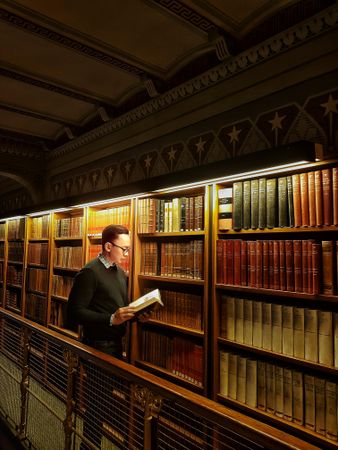 Man holding open book standing in library