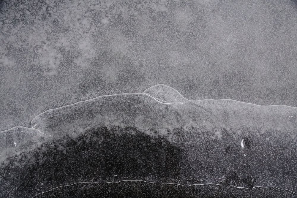 Fragment of thin ice on dark frozen river