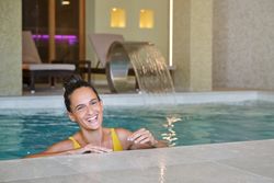 Laughing female swimming in pool of spa resort