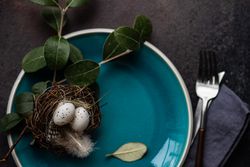 Easter table setting with nest and small eggs on blue plate