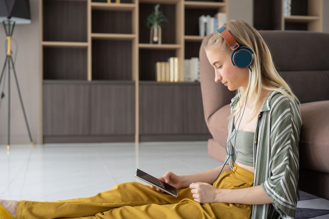 Happy young woman listening to music with headphone on sofa