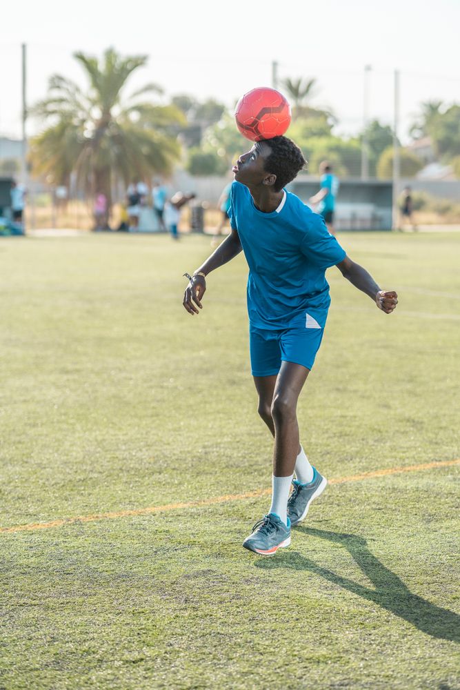 Black teenager jugging football ball on head