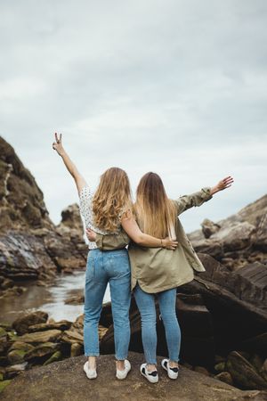 Young sisters standing on stone on spring day