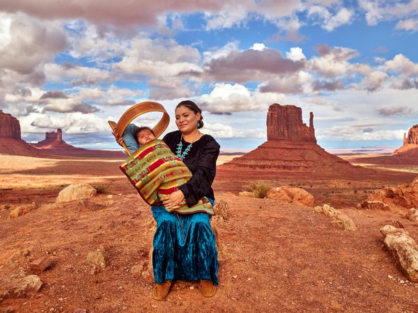 Young Navajo mother holding her baby in cradleboard in Monument Valley
