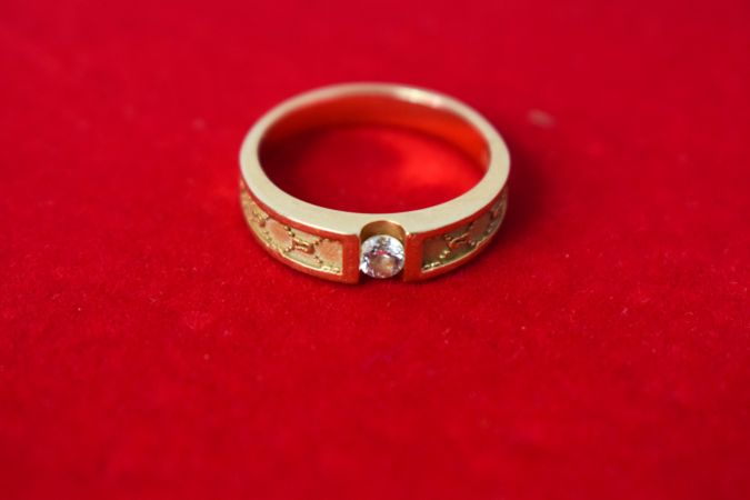 Man's diamond gold ring on red background with copy space