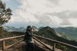 Young stylish woman taking photo on camera of wonderful mountains