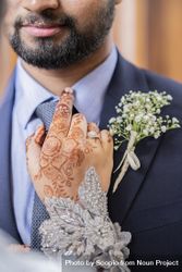 Bride's henna tattooed hand on the shoulder of groom 0JvBn0