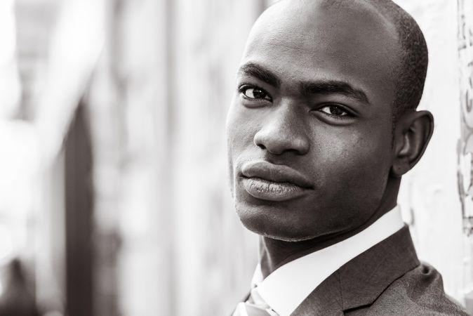 B&W picture of male in business attire standing and looking at camera