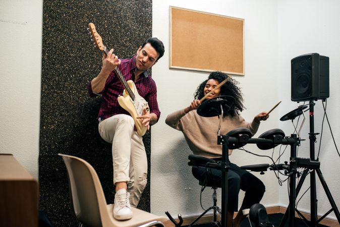 Man playing guitar and woman playing drums