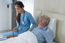 Asian medical professional checking blood pressure of older male patient