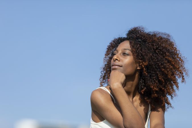 Female with curly hair in deep thought outside