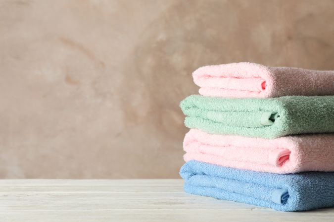 Stack of clean towels against brown background, space for text