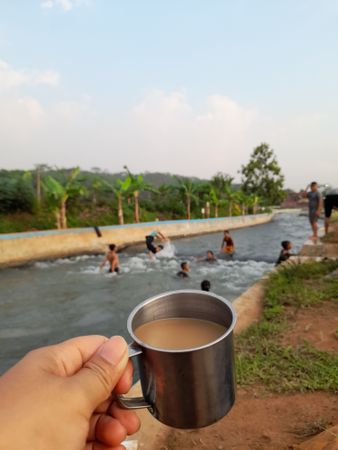 enjoying a cup of coffee by the river while watching people swimming